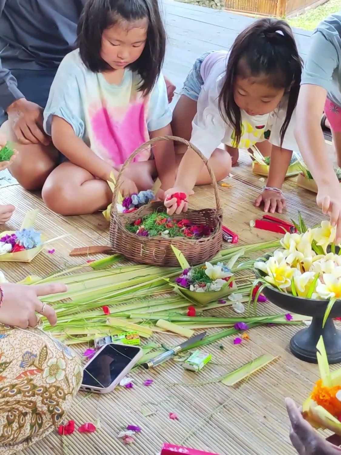 Guests arranging flowers in palm-leaf offerings during a Canang Sari class at Ubud Raya Resort