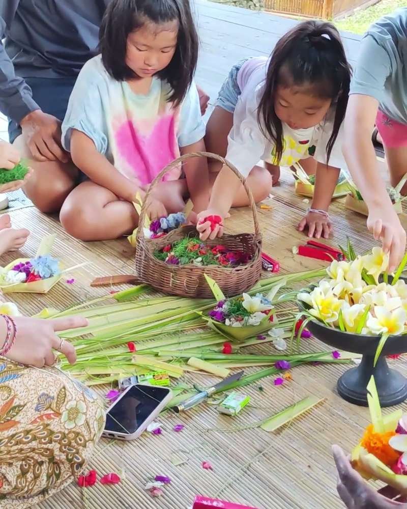Guests arranging flowers in palm-leaf offerings during a Canang Sari class at Ubud Raya Resort