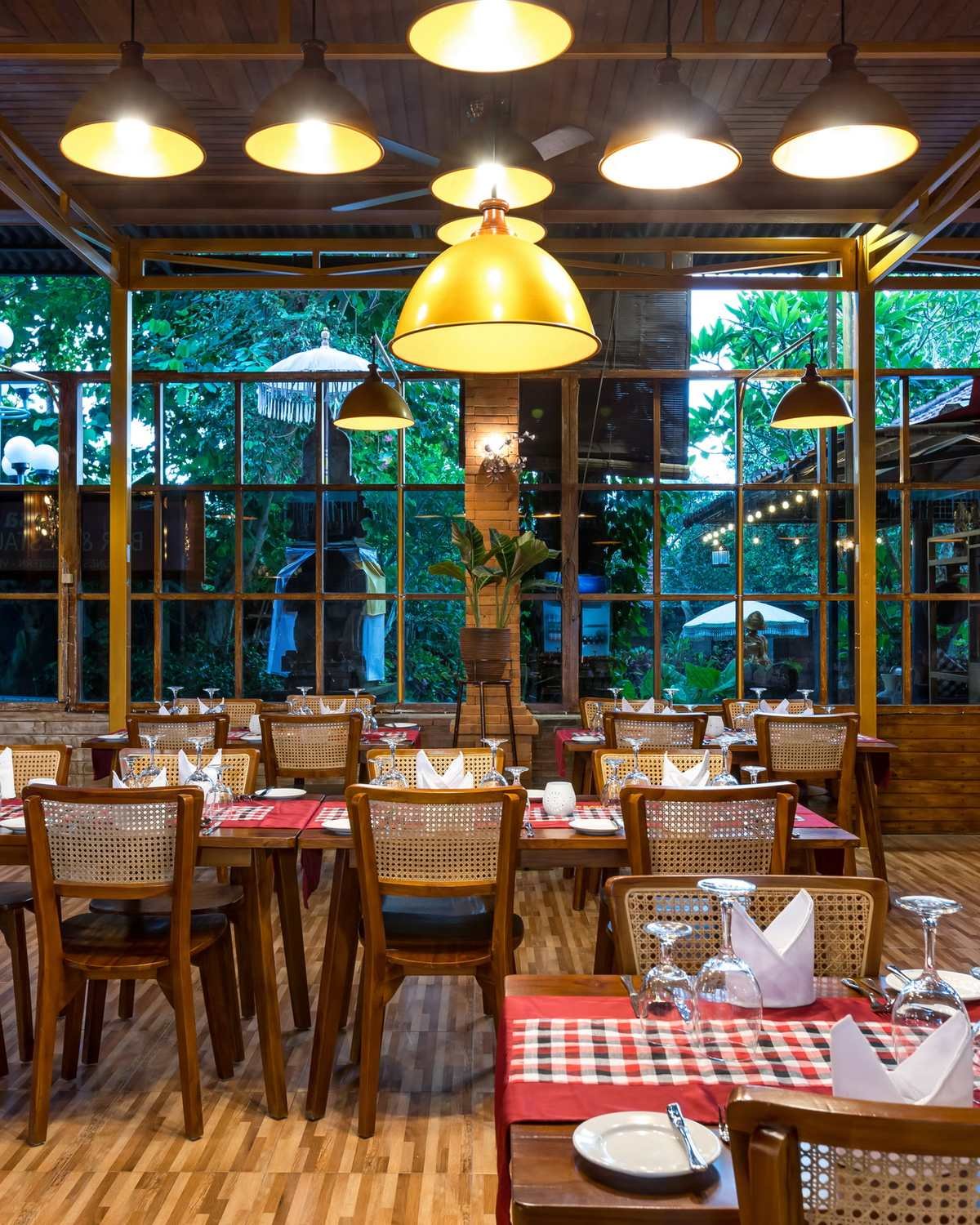 The dining room of Royal Indian Masala with brass pendant lamps and tall garden windows
