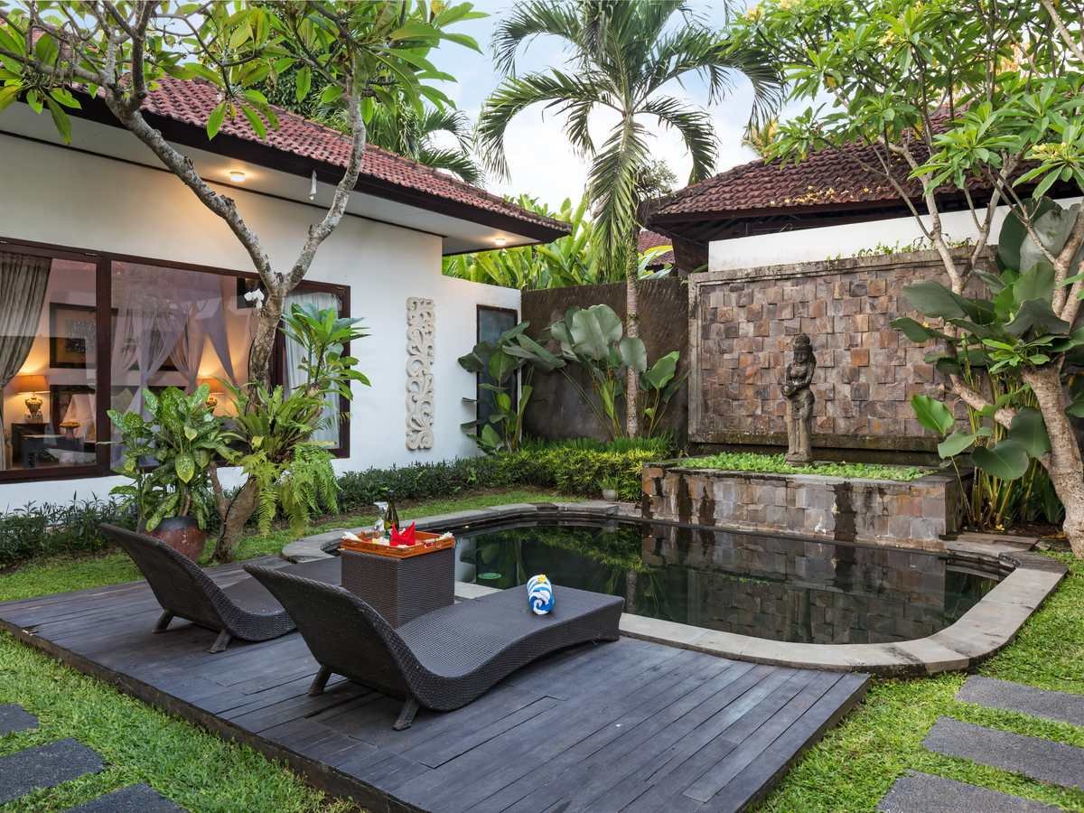 Two-Bedroom Pool Villa with loungers beside a stone water feature