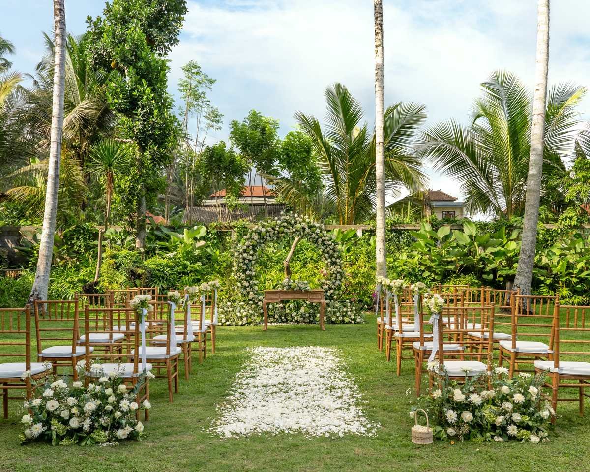 A garden ceremony set with white chairs and flowers on the resort lawn