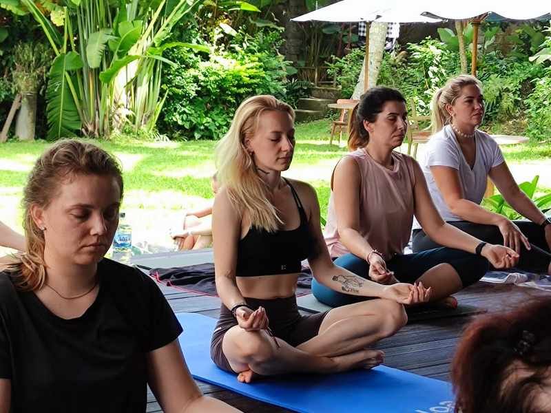 Guests in a seated pose during yoga in the pavilion